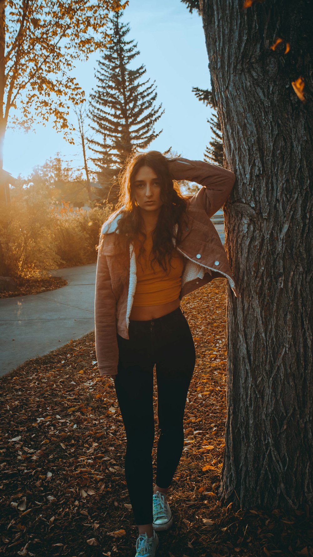 woman in brown jacket standing beside tree