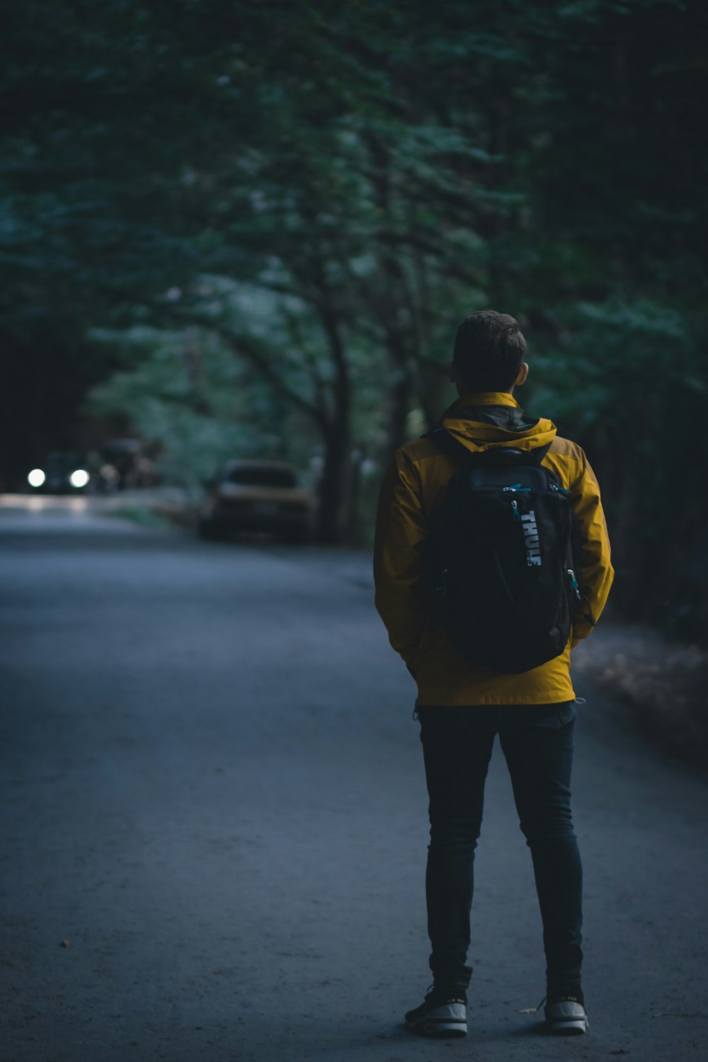 man wearing yellow pullover walking on street