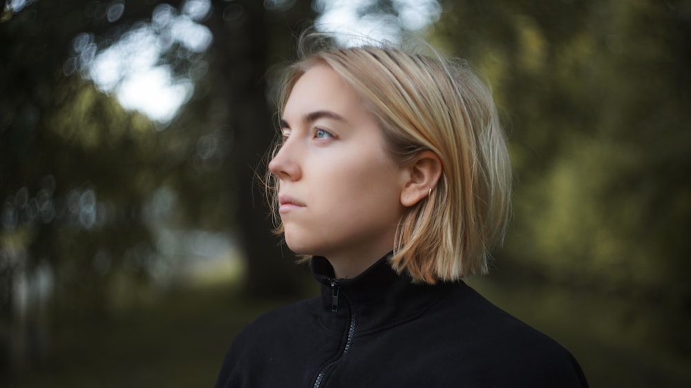 woman in black shirt standing near trees