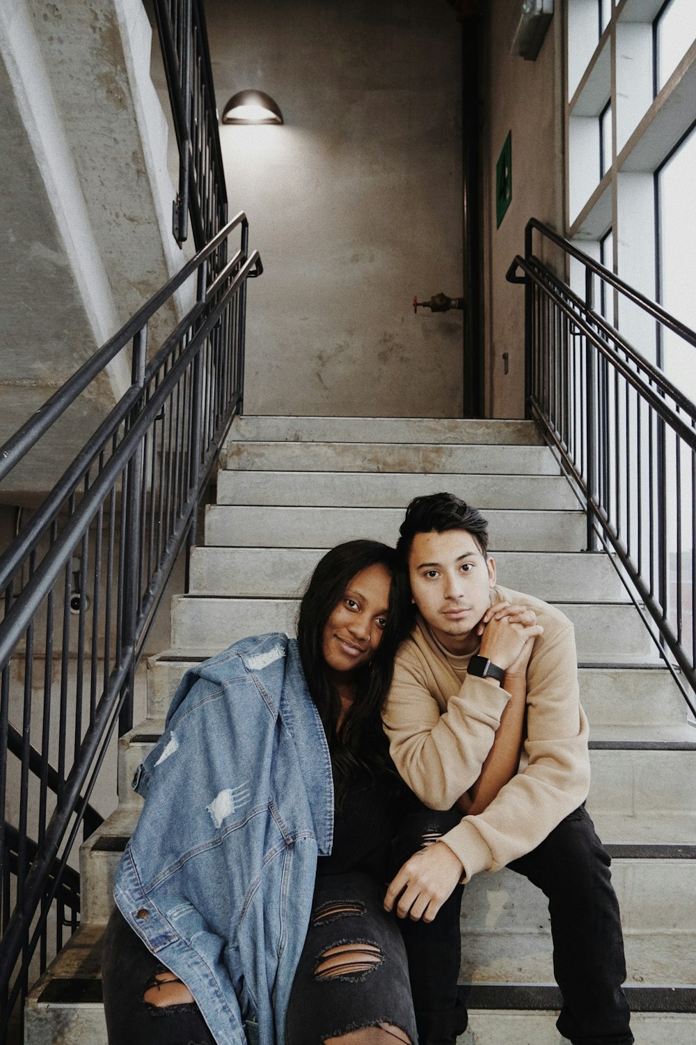 man and woman sitting on concrete steps indoors