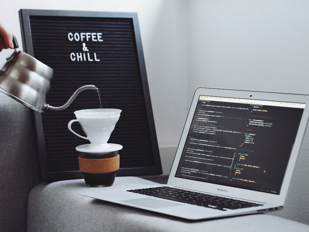 MacBook Air beside white coffee cup