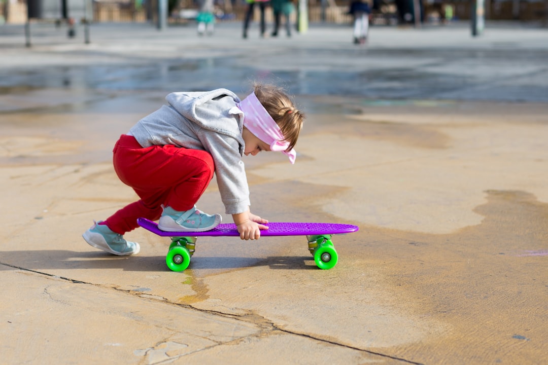 toddlers wearing gray pullover and red track pants riding purple cruiser board