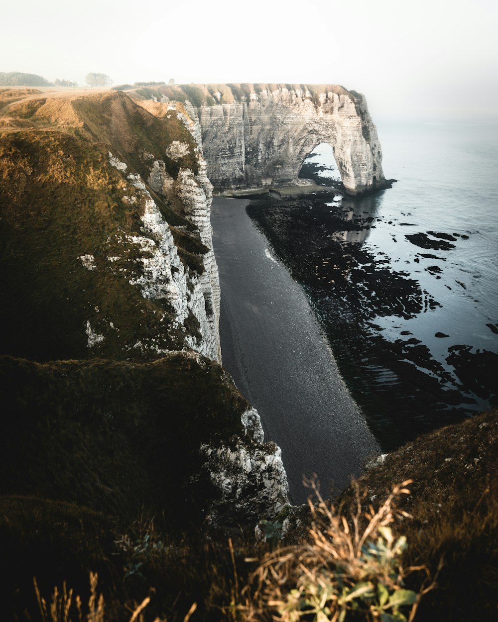grey cliff beside ocean during daytime