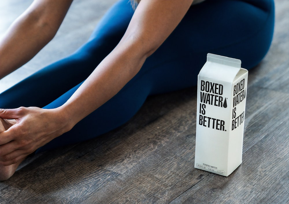 person wearing blue leggings sitting near boxed water