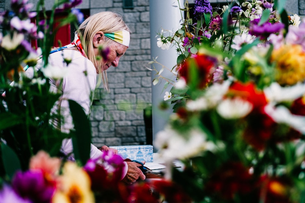 selective focus photography of woman standing beside petaled flowers