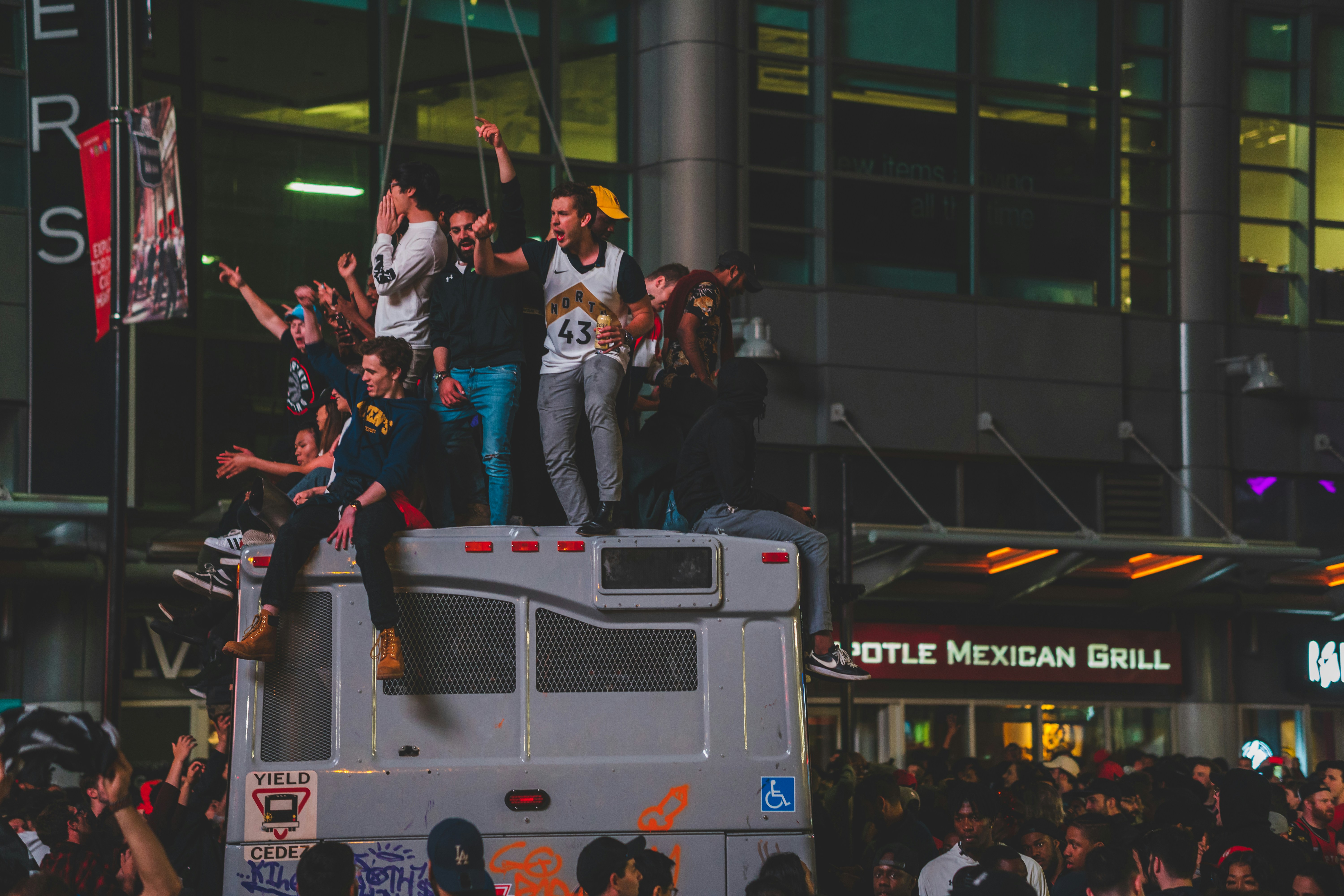 Toronto Raptors fans celebrating on top of a bus after we took home the 2019 NBA championship.