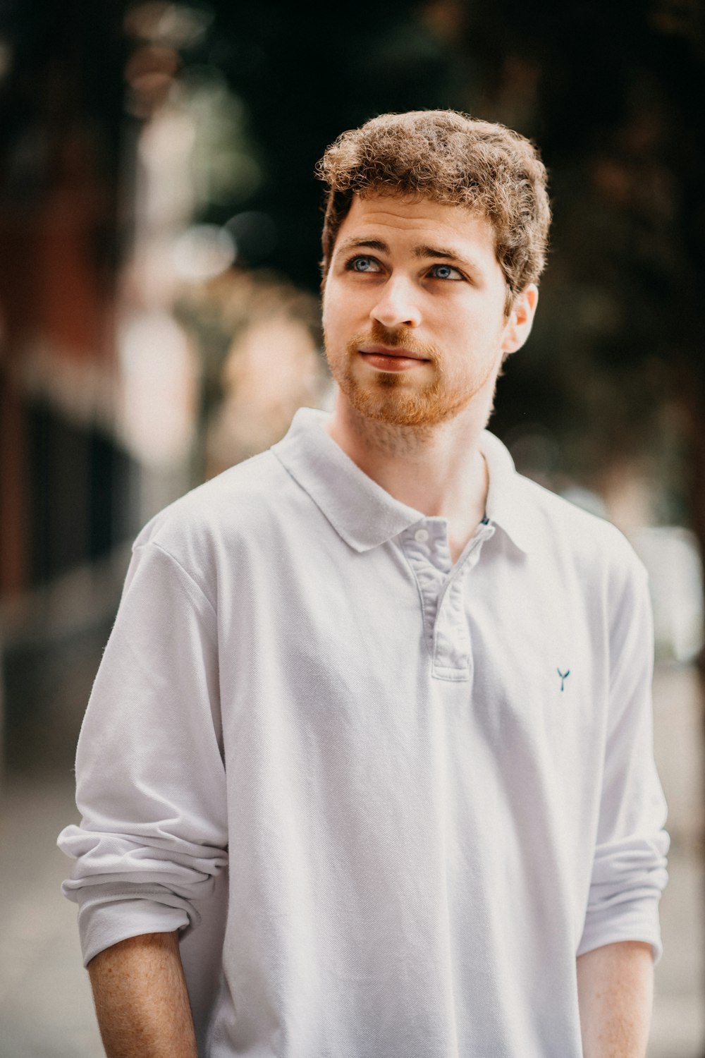 man in white collared long-sleeved shirt standing outdoors