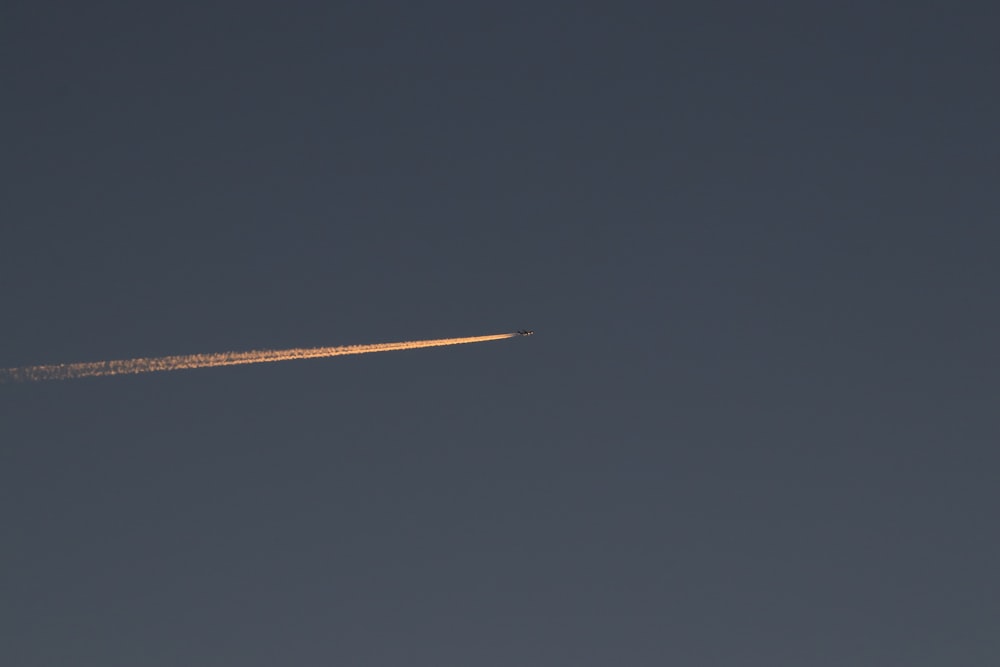 Un jet che vola attraverso un cielo blu con un contrail
