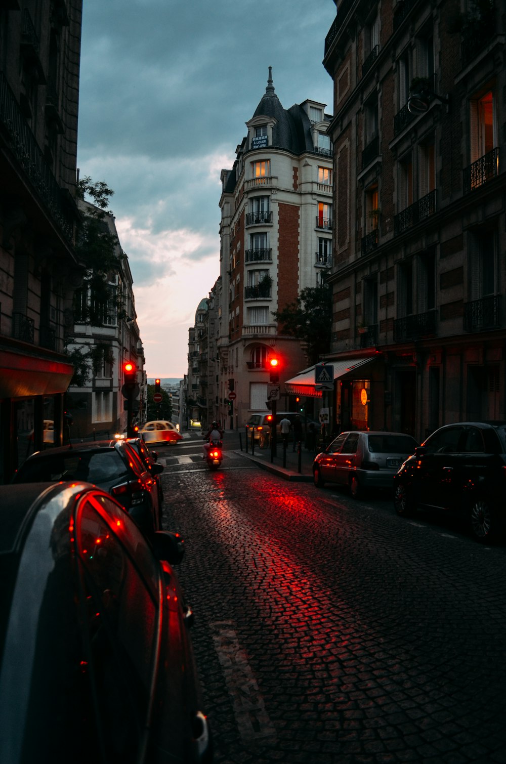 vehicles on road between buildings during blue hour