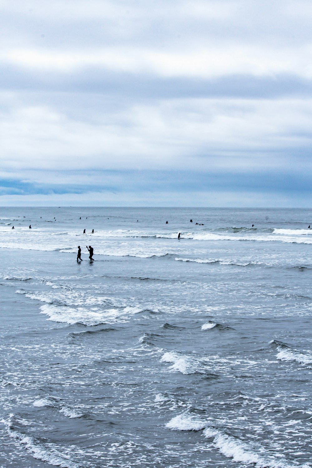 a group of people standing on top of a beach next to the ocean