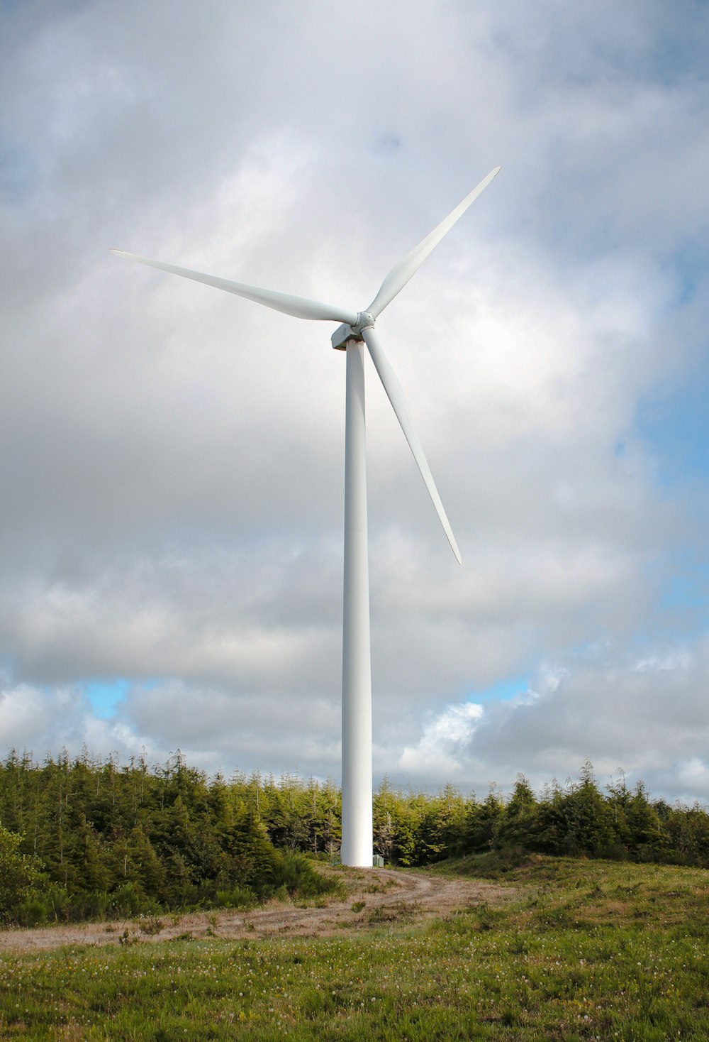 white wind turbine under cloudy sky