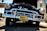 A classic vintage car with a shiny chrome grille and headlights is parked in an outdoor setting. The car's hood is open, displaying some of the engine components. The license plate reads 'California' and the scene is lit by bright sunlight, highlighting the reflective surfaces of the car.