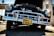 A classic vintage car with a shiny chrome grille and headlights is parked in an outdoor setting. The car's hood is open, displaying some of the engine components. The license plate reads 'California' and the scene is lit by bright sunlight, highlighting the reflective surfaces of the car.