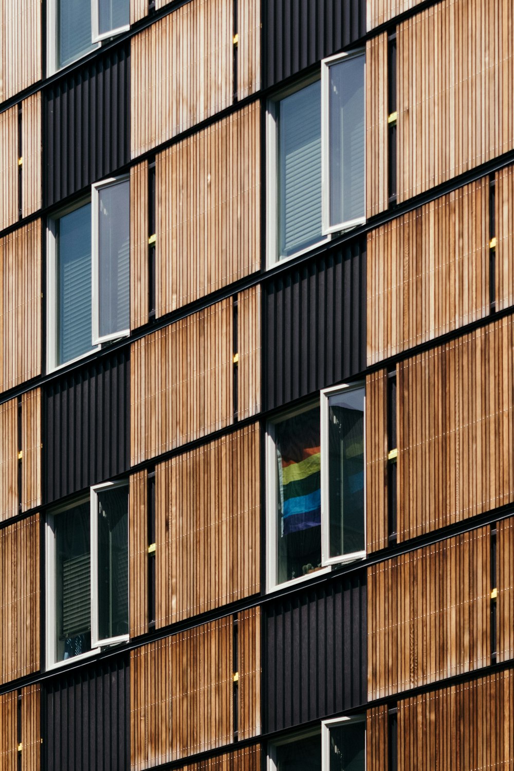 a tall building with lots of windows next to a rainbow flag
