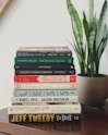 stack of assorted-title books beside snake plants