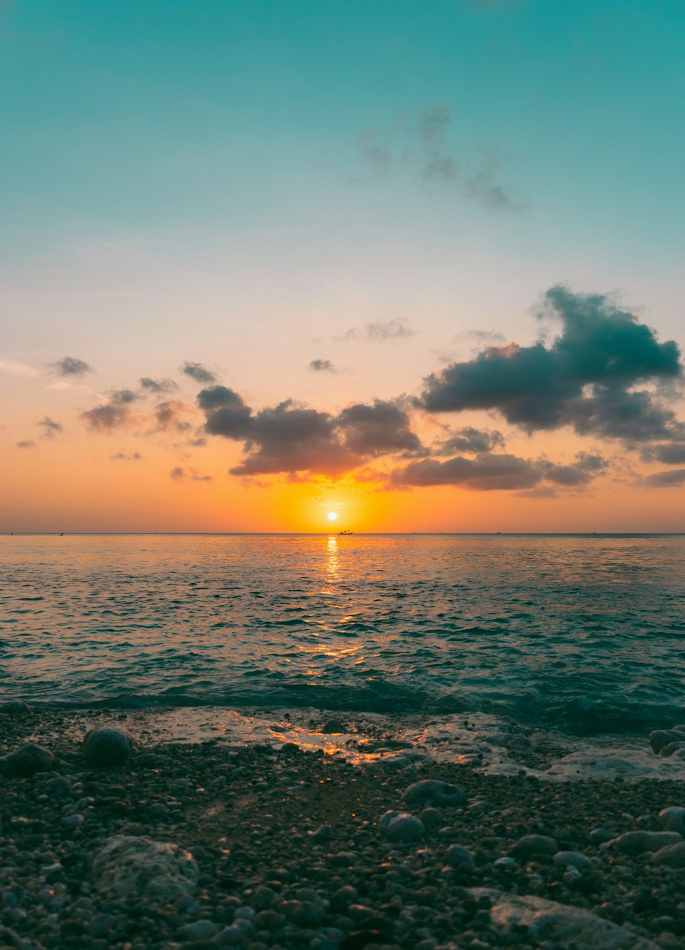 the sun is setting over the ocean on the beach