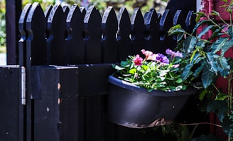 Close-up of a worker painting a fence a deep purple, contrasting against the black accents.