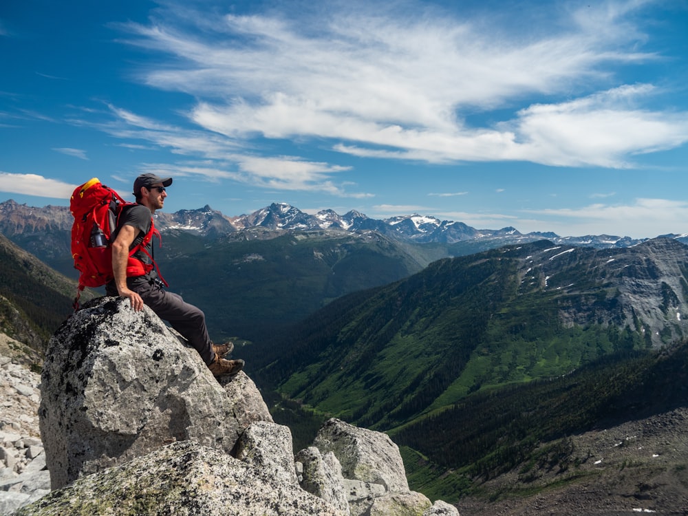 man sitting on gray rock formation