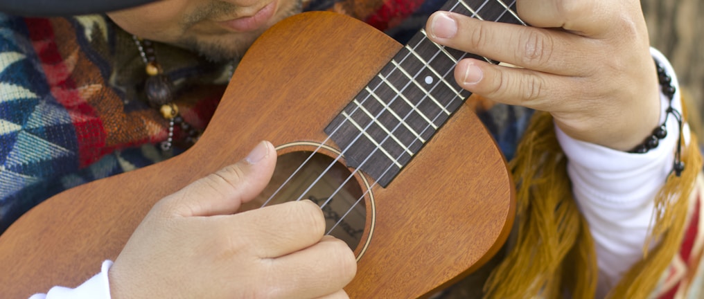 person playing brown ukulele