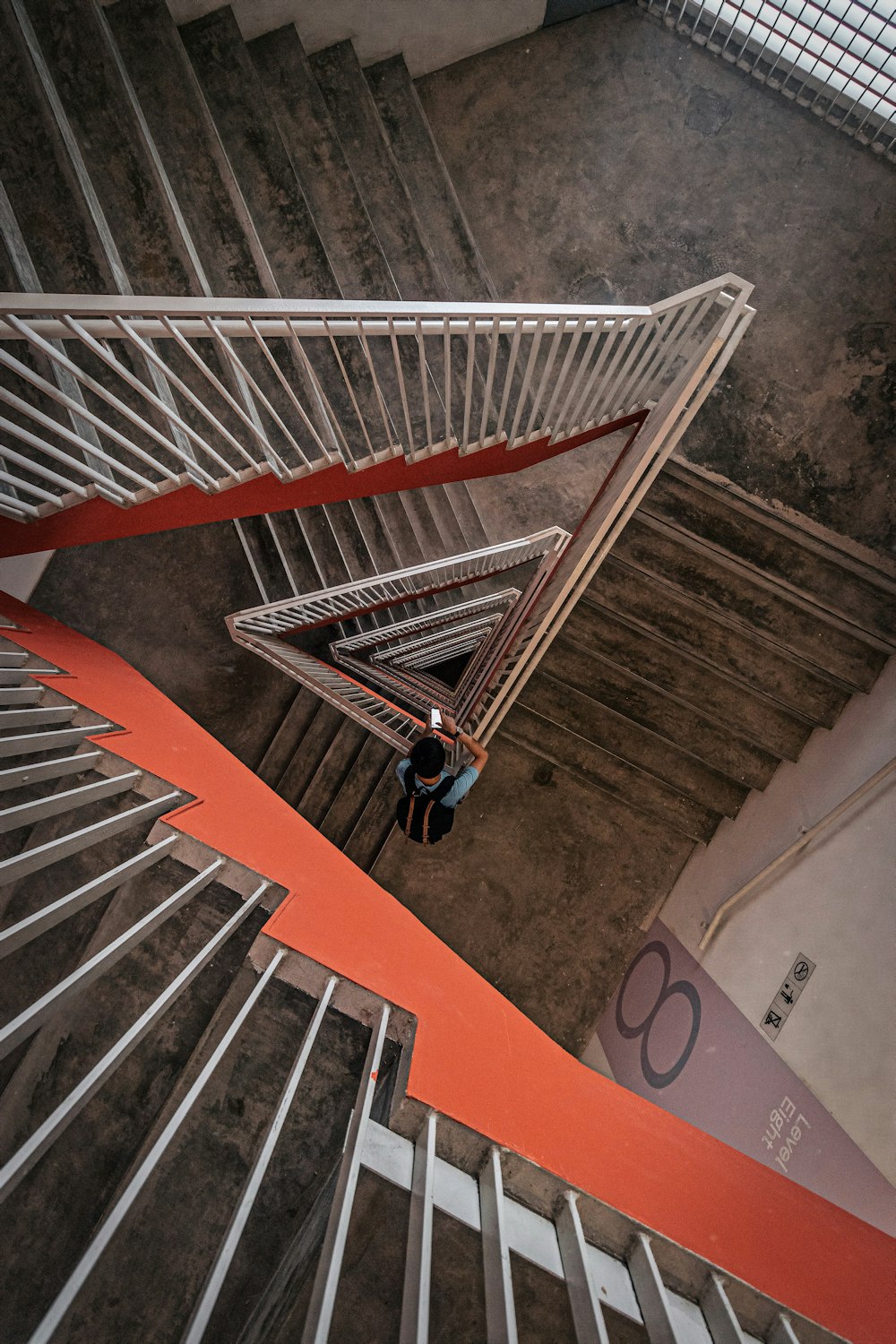 person standing beside stair rail using smartphone