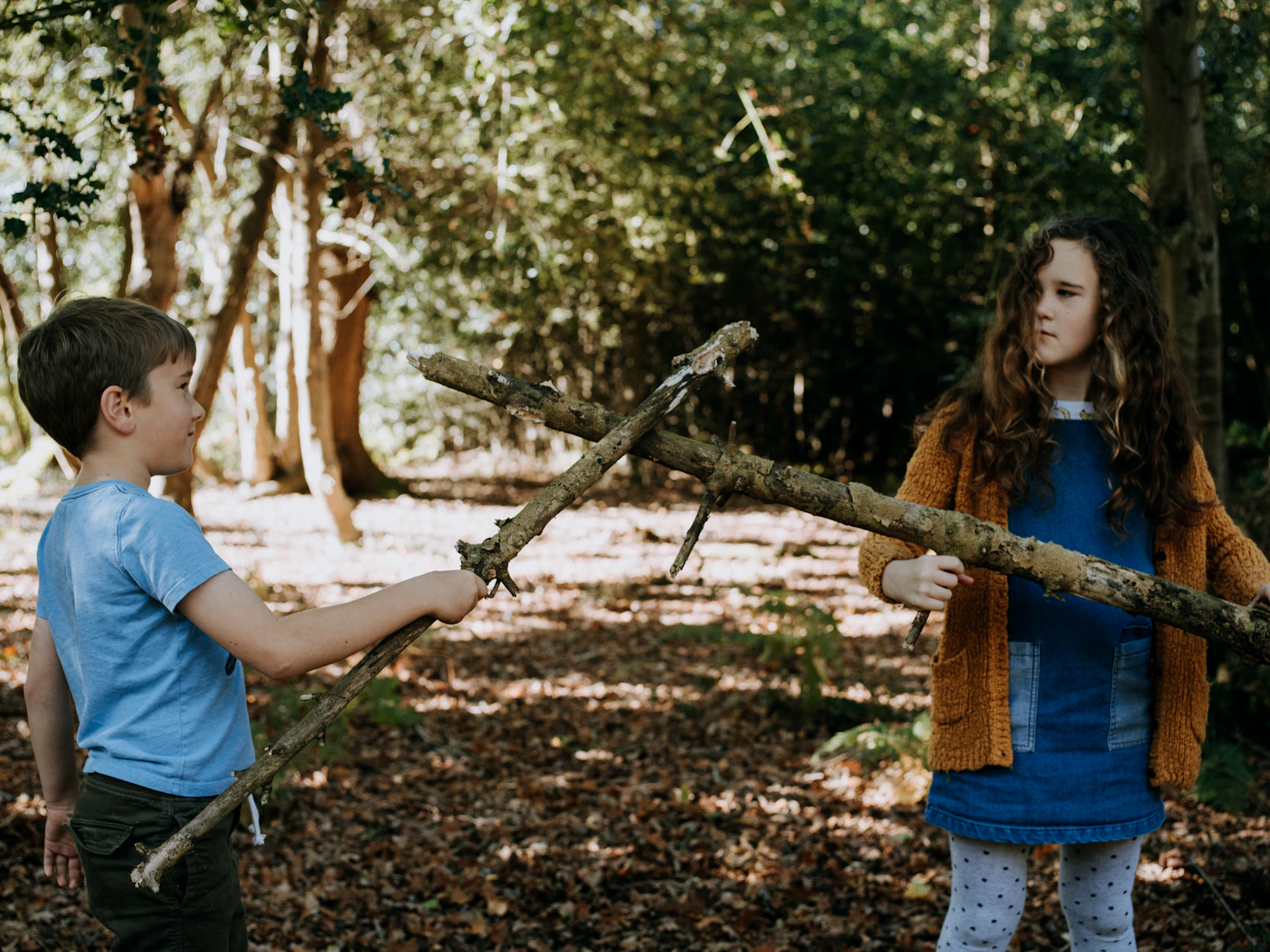 Een jongen en een meisje spelen met stokken in het bos