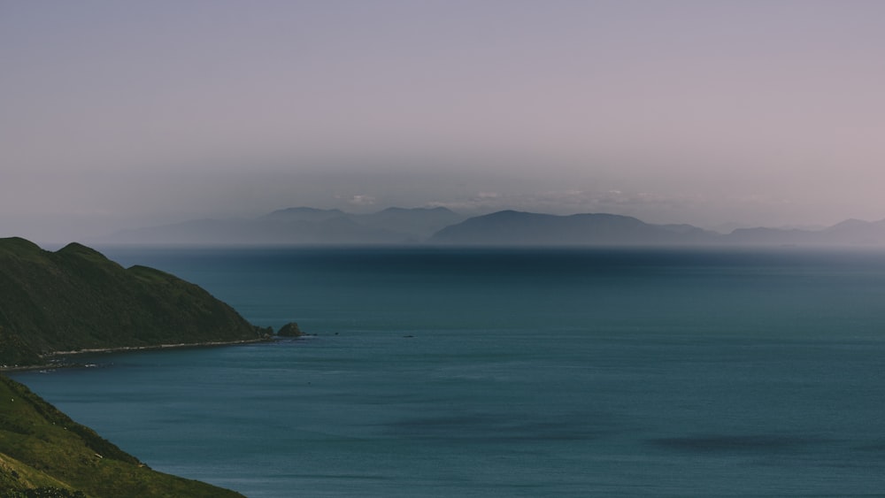 白と灰色の空の下で山を眺める青い海