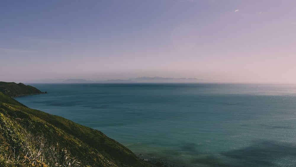 green mountain and body of water