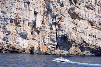 A sleek modern RIB boat cruising near the rocky cliffs of Sella del Diavolo under a clear blue sky