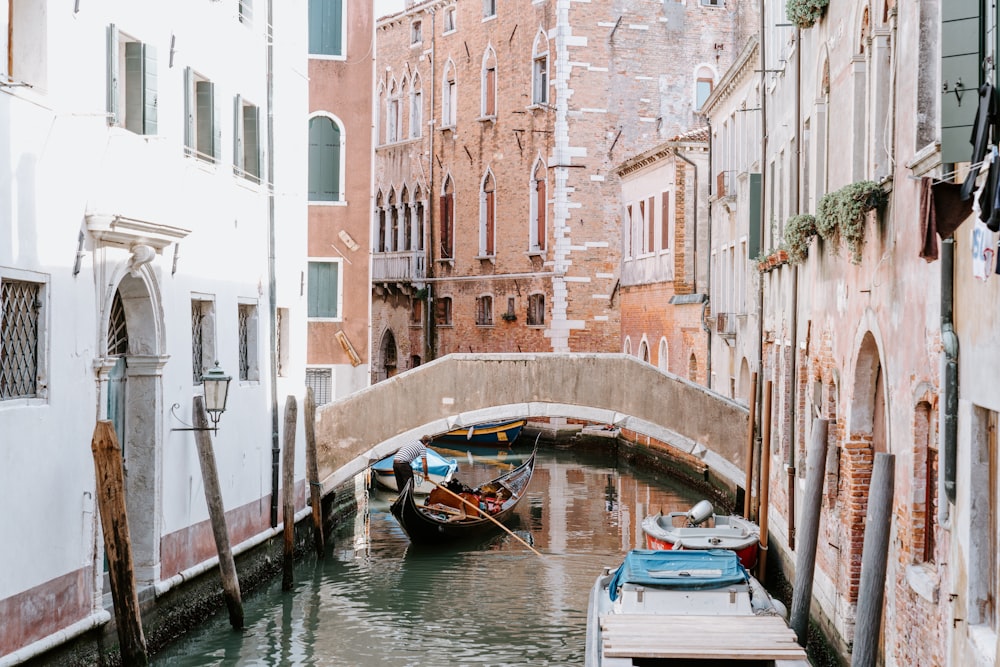 boats on canal between buildings