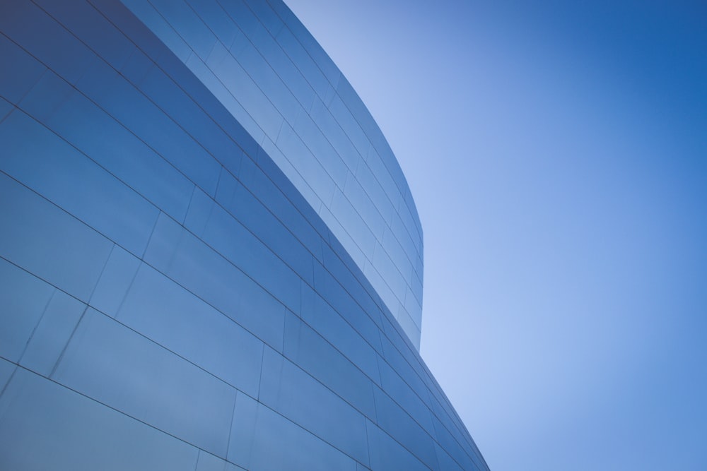 fotografia de baixo ângulo de edifício com paredes de vidro azul durante o dia