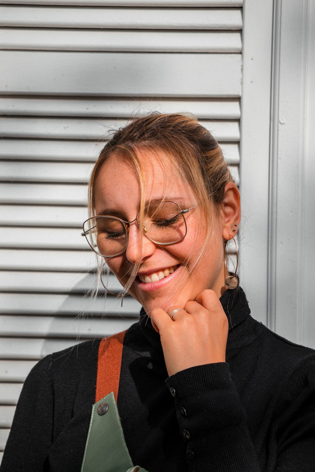 smiling woman wearing black long-sleeved shirt near white wooden window