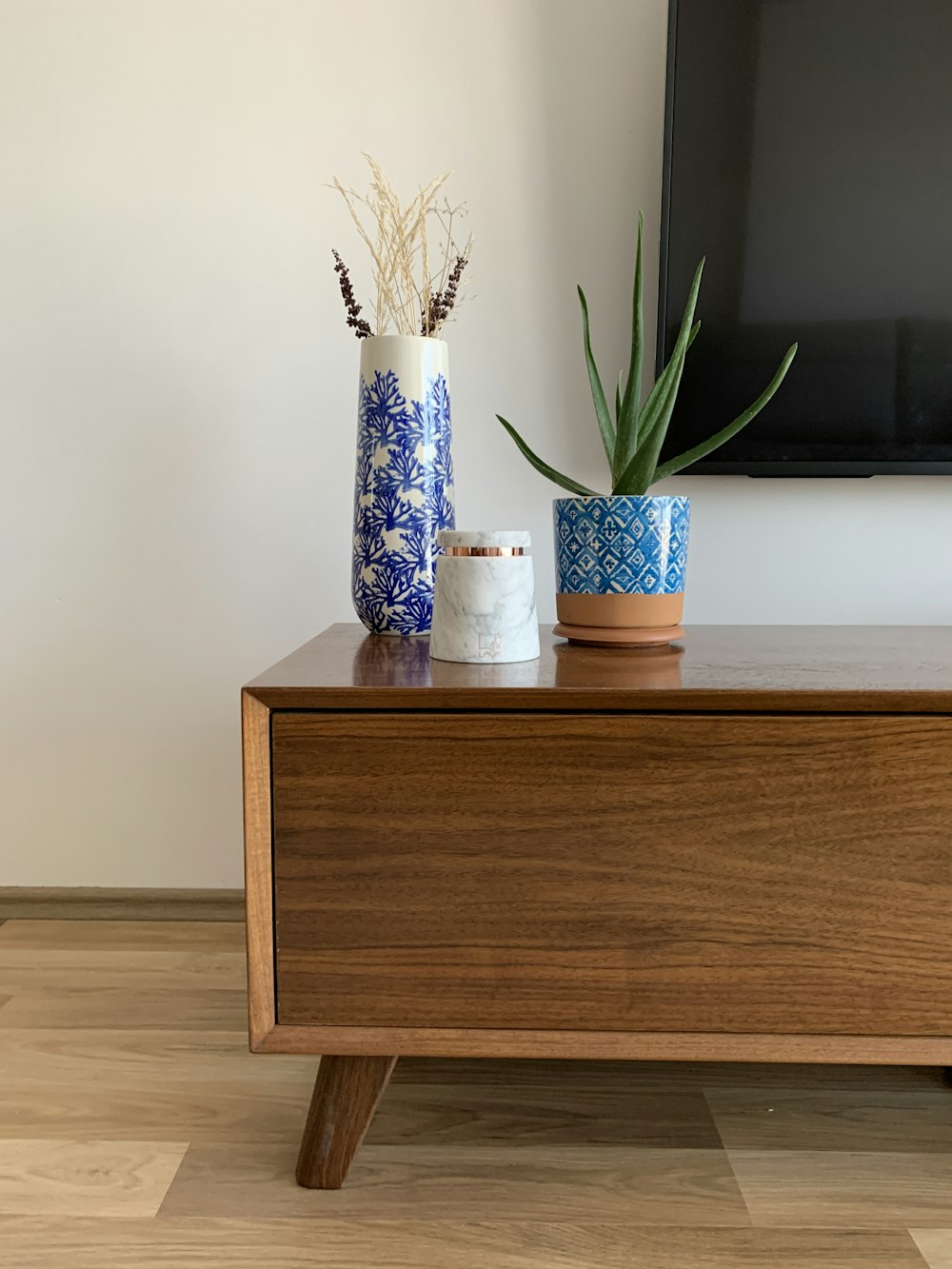 green leafed plant in blue top on top of brown table