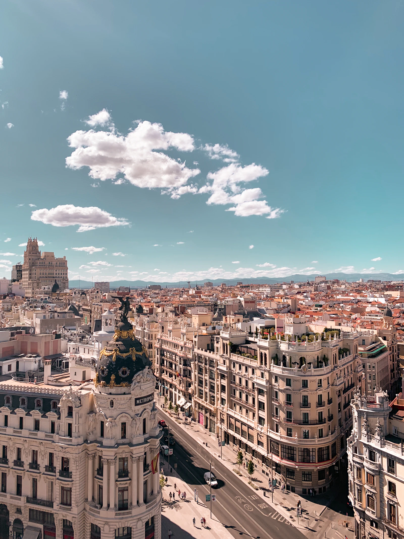 Daytime rooftop view down Gran Vía in Madrid, with the domed Metropolis building in the foreground