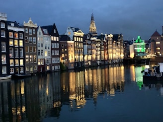 A scenic view of the canals and colorful buildings in Amsterdam at sunset.
