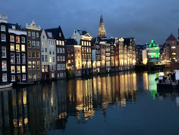A scenic view of the canals and colorful buildings in Amsterdam at sunset.