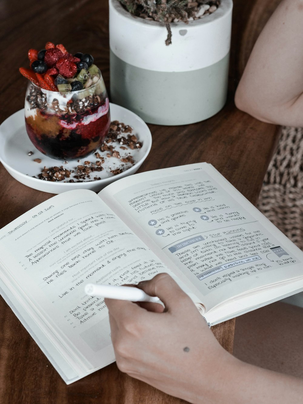 a person is reading a book with a dessert in the background