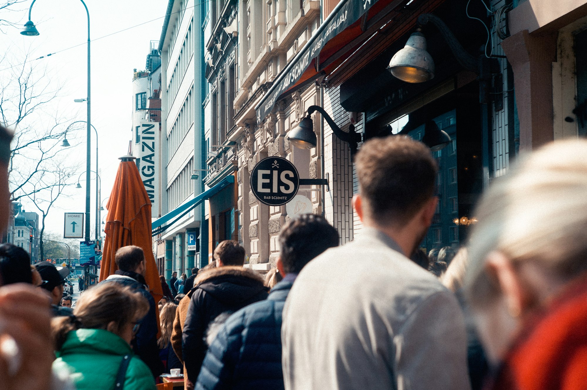 A group of people stand in a line outside a popular restaurant.