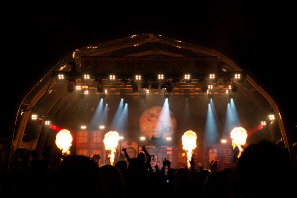 A nighttime concert stage illuminated with vibrant spotlights and surrounded by a secure barricade.