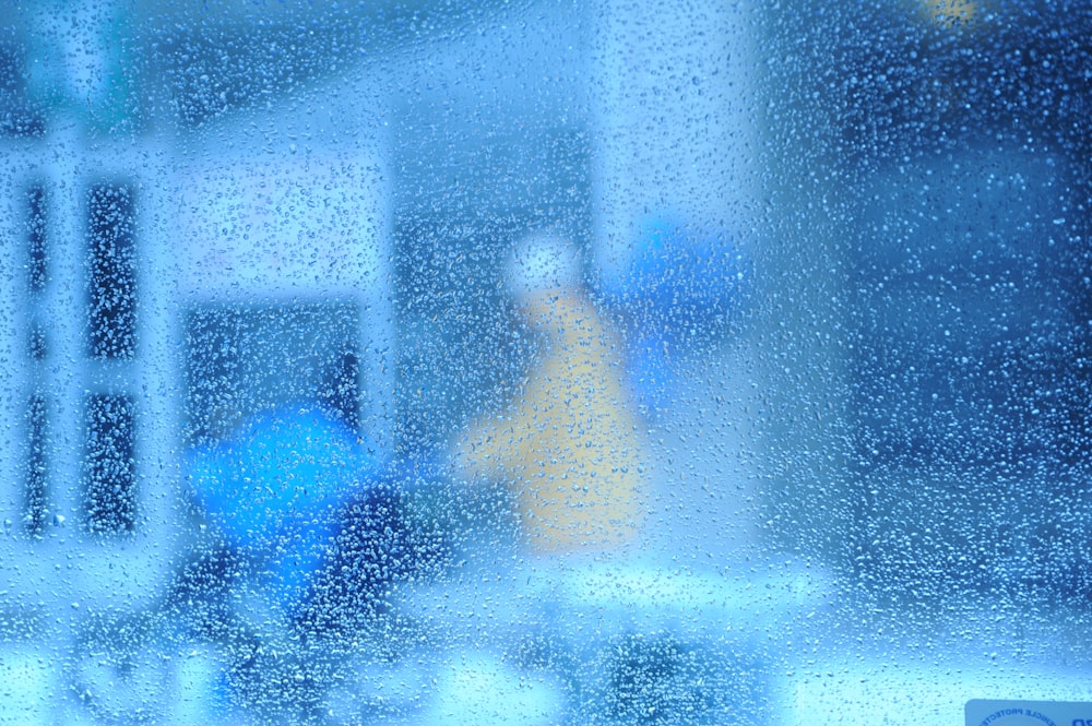 a blurry image of a person walking in the rain through a window