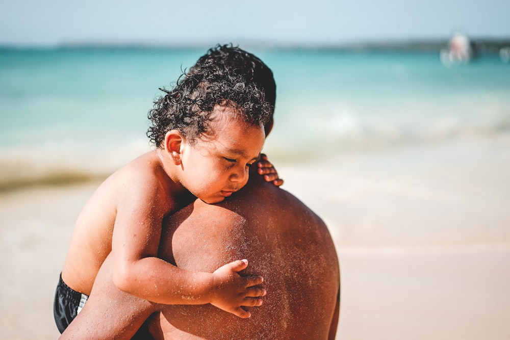 Hombre cargando a un niño en la orilla del mar