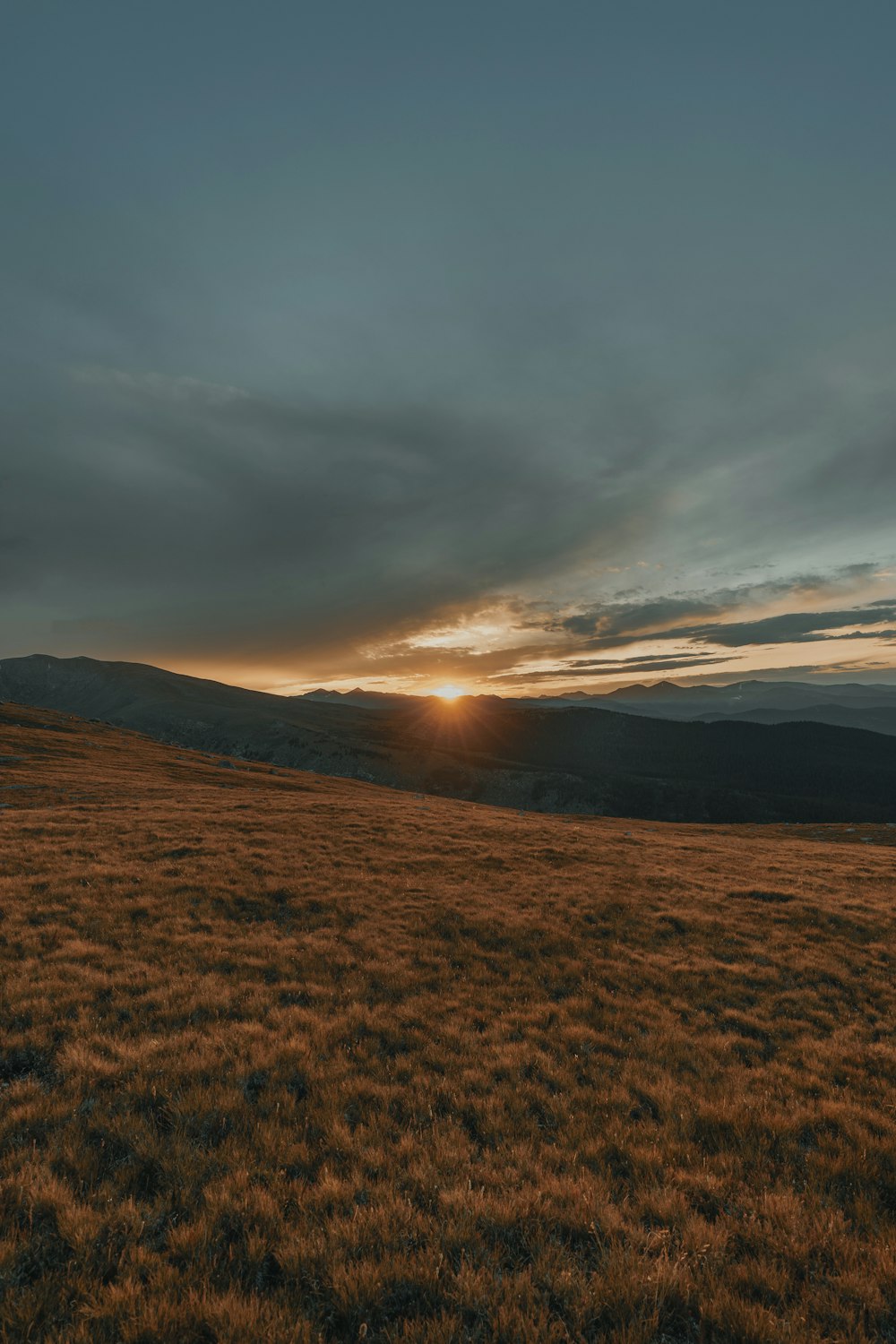 brown grass land across mountain during sunset