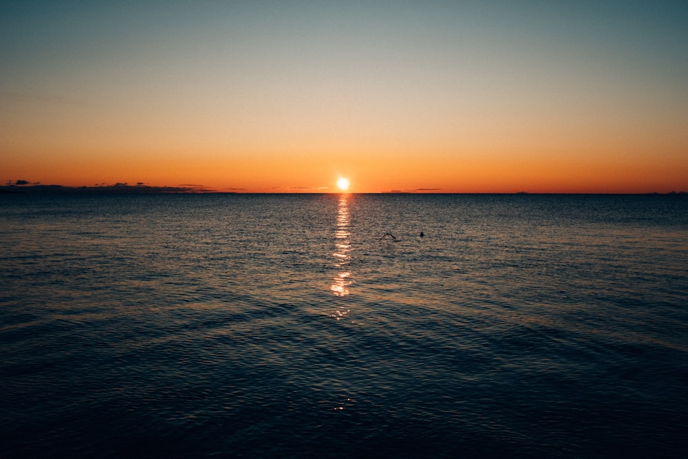 body of water under brown sky at golden hour