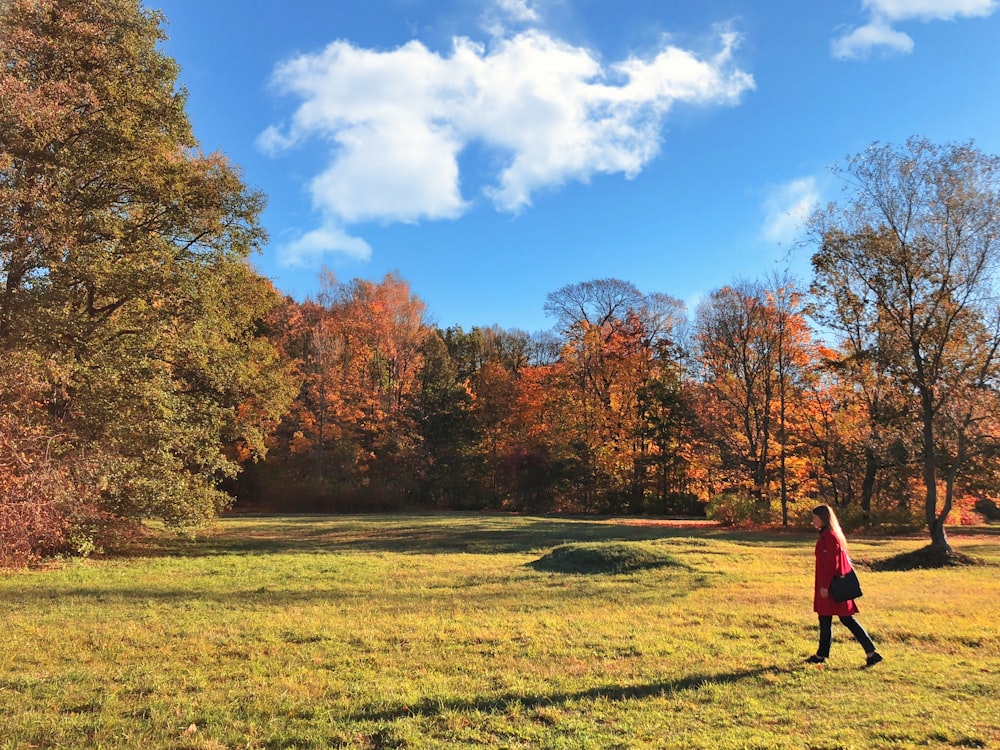 woman wearing red coat beside trees