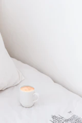 A white ceramic mug featuring a bright custom print, placed beside a steaming cup of coffee.