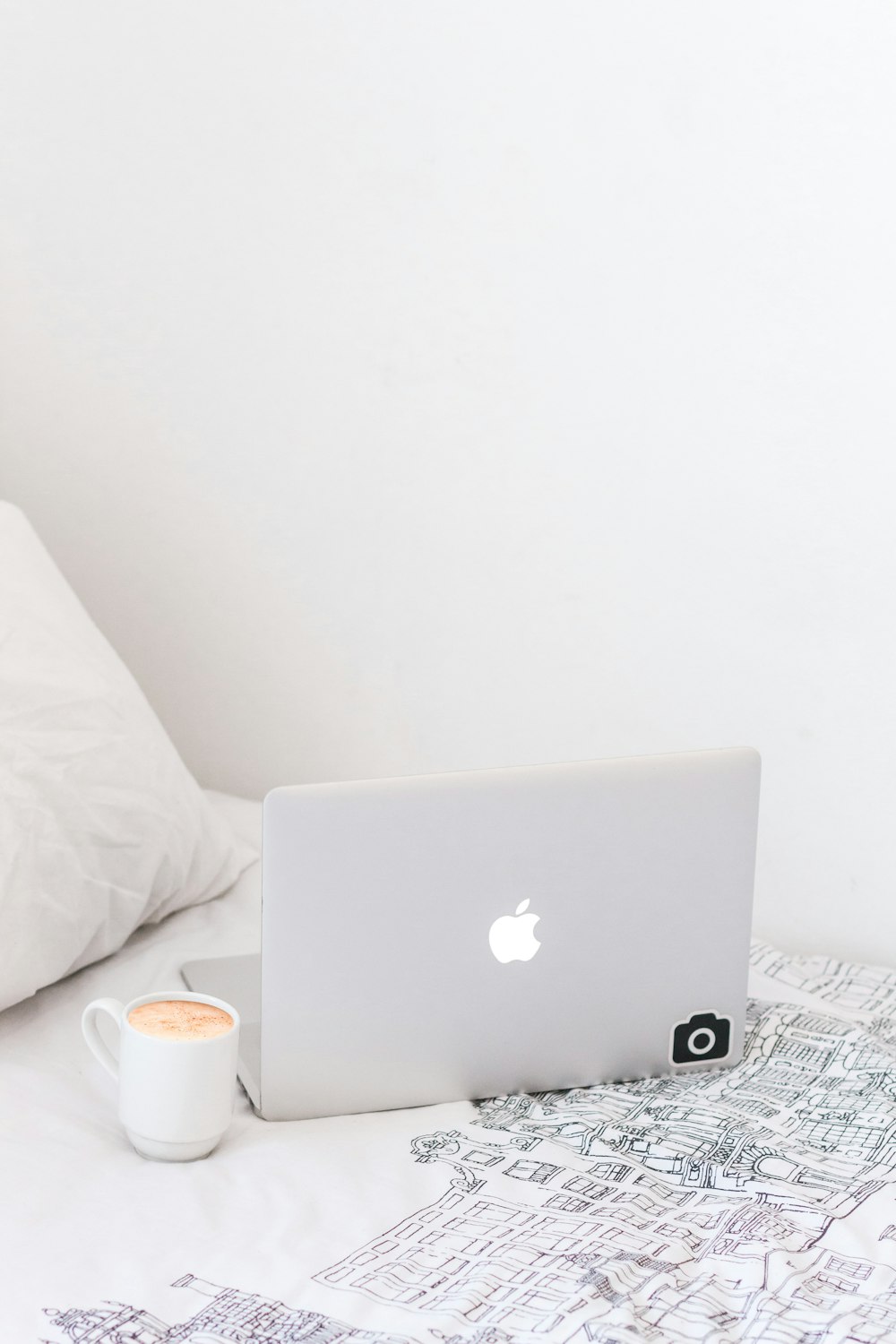 silver MacBook beside cup