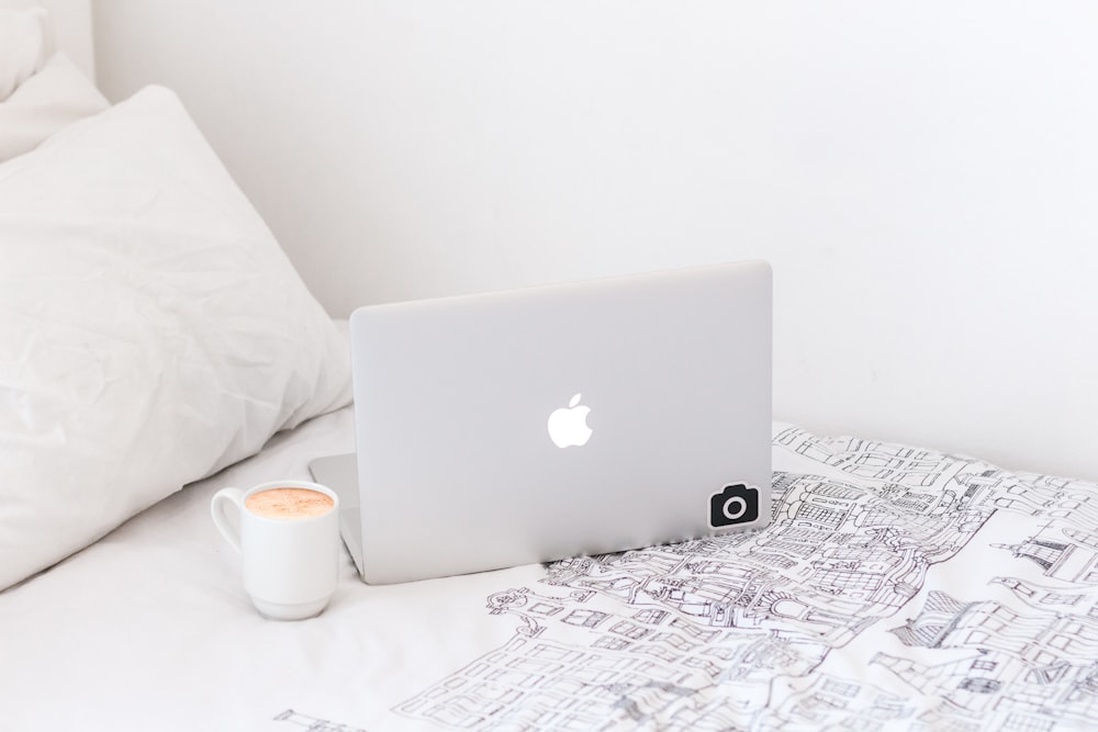 silver MacBook beside mug