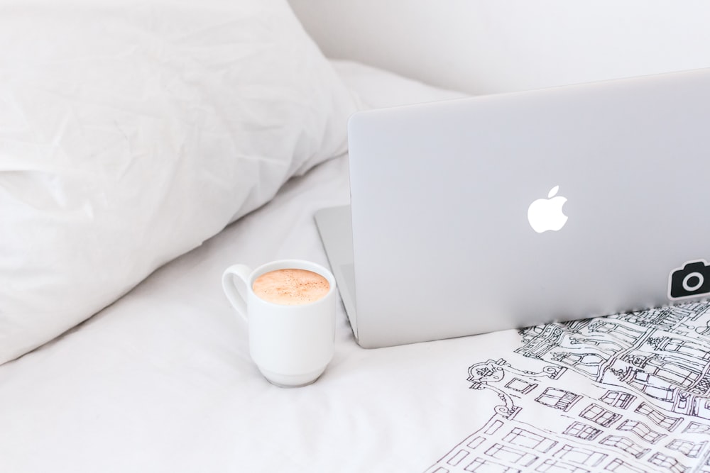 caneca de café de cerâmica branca ao lado do MacBook Air
