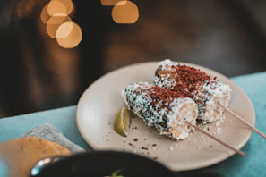 Traditional elote on a stick with butter and salt, wrapped in a paper napkin.