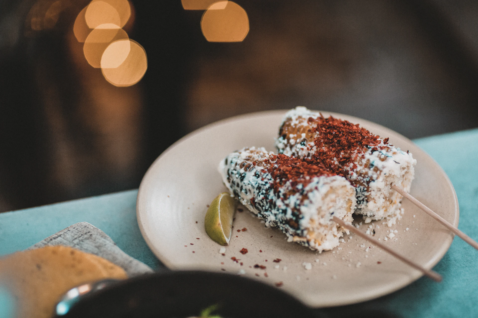 A vibrant close-up of a colorful elote topped with cheese, chili powder, and lime, steam rising gently.
