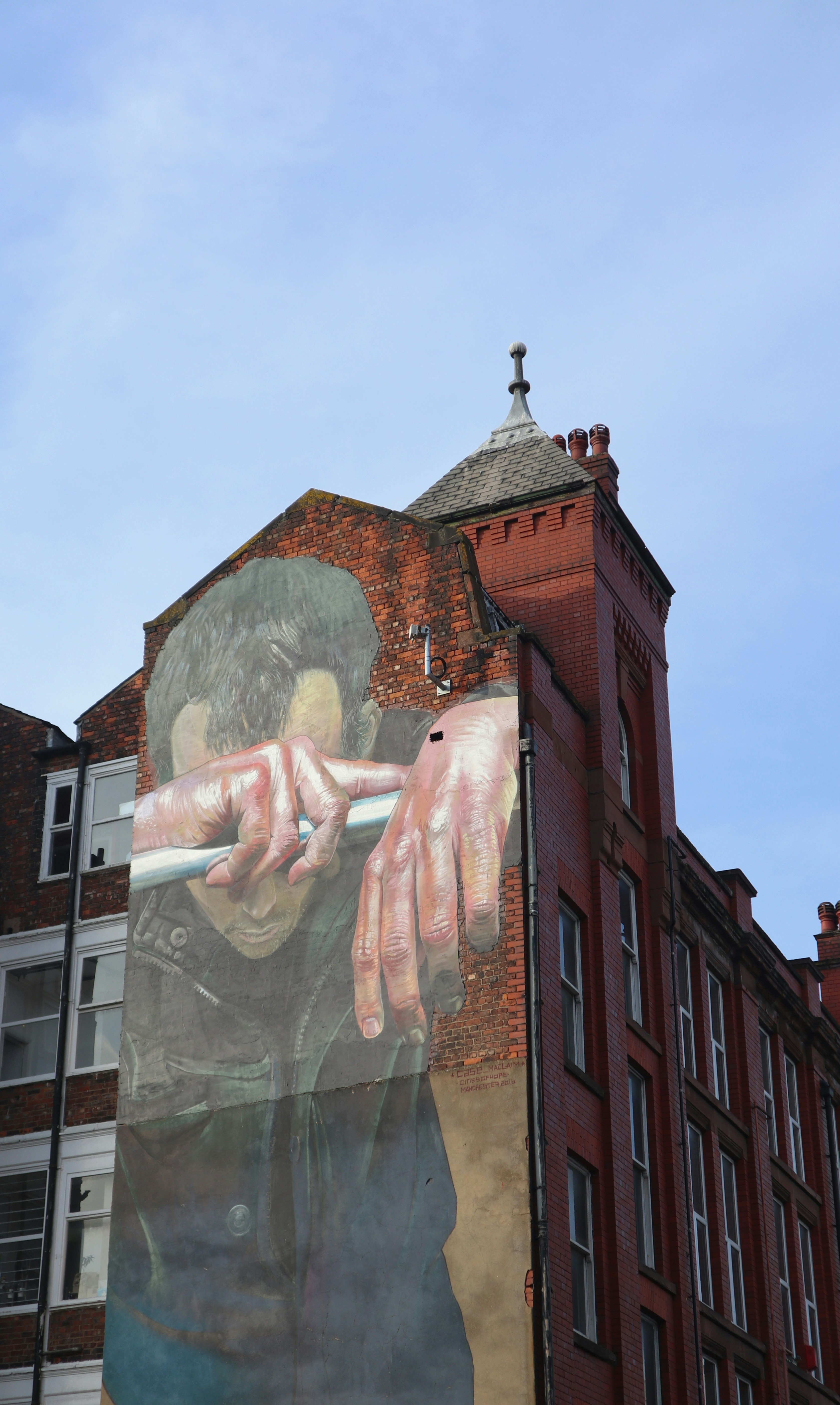 Giant street art mural, built into red brickwork in Manchester's Northern Quarter.